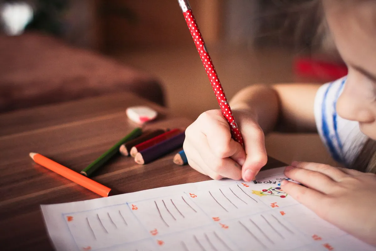 Tarea escolar con lápices de colores sobre el escritorio del alumno