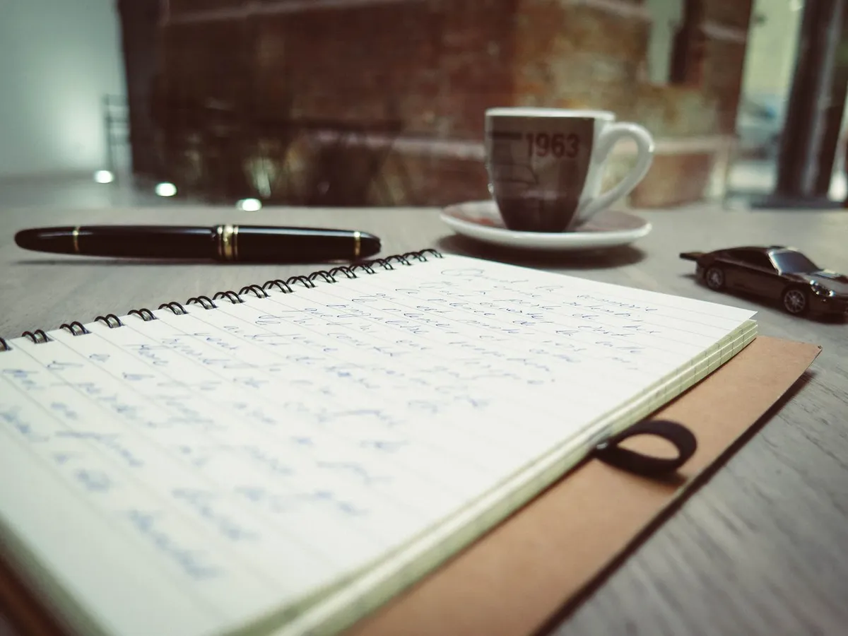 Cuaderno, birome y café sobre la mesa de trabajo de Lucía